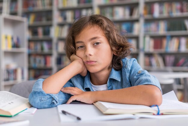 Vista frontal del niño aburrido mientras hace sus deberes