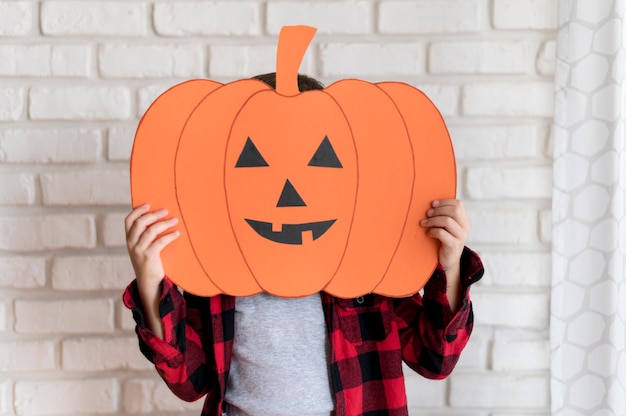 Vista frontal del niño con calabaza de papel