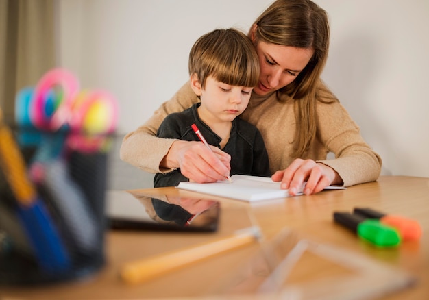 Vista frontal del niño en casa con tutora