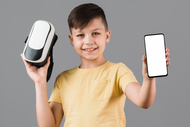 Vista frontal del niño con casco de realidad virtual y teléfono inteligente