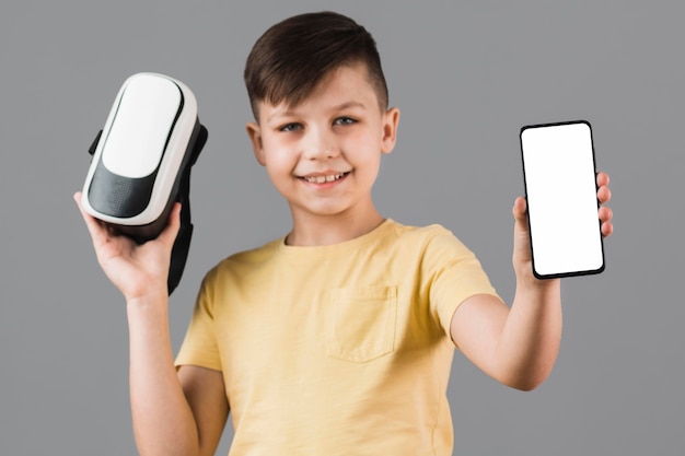 Vista frontal del niño con casco de realidad virtual y teléfono inteligente