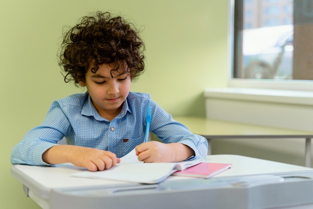 Foto gratuita vista frontal del niño en clase en la escuela