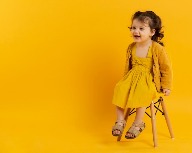 Foto gratuita vista frontal del niño feliz posando mientras está sentado en la silla