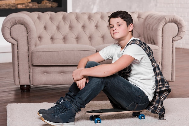 Vista frontal del niño con gafas de sol sentado en patineta