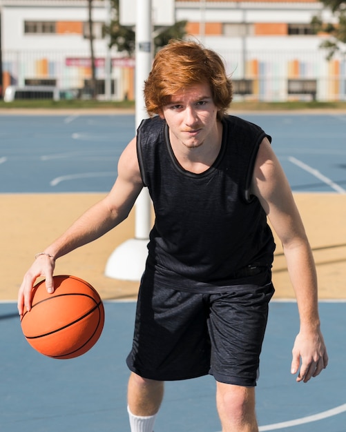 Vista frontal del niño jugando baloncesto