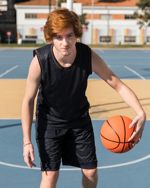 Vista frontal del niño jugando baloncesto