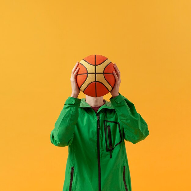 Vista frontal niño jugando con pelota de baloncesto