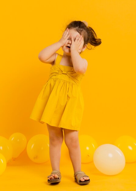 Vista frontal del niño lindo posando con globos