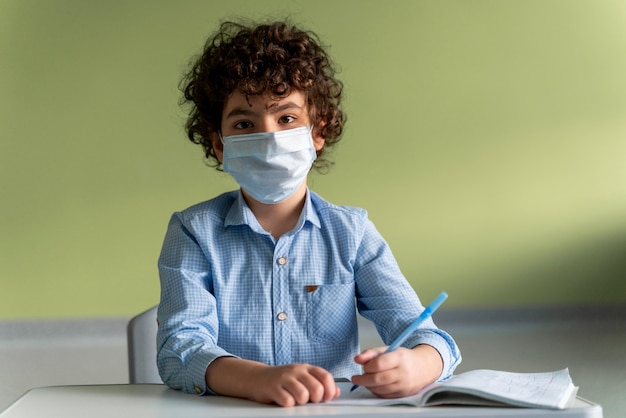 Vista frontal del niño con máscara médica en la escuela durante la pandemia