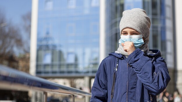 Vista frontal del niño con máscara médica y tos