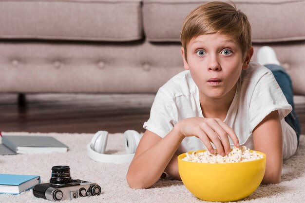 Vista frontal del niño moderno comiendo palomitas de maíz