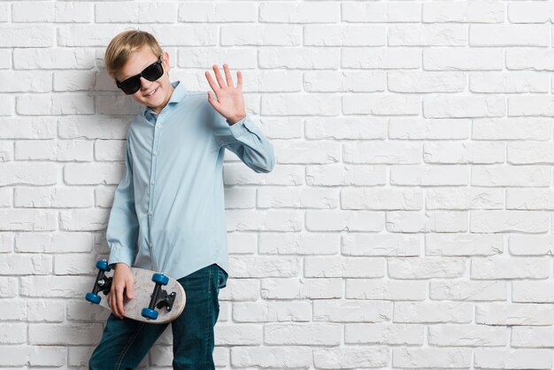 Vista frontal del niño moderno con patineta y espacio de copia