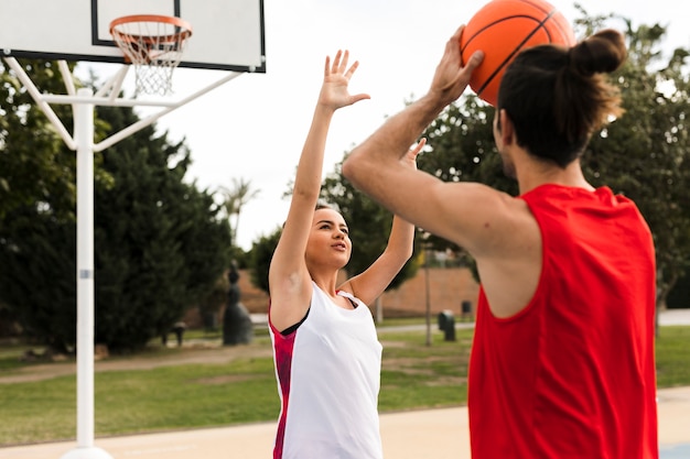 Vista frontal del niño y niña jugando baloncesto