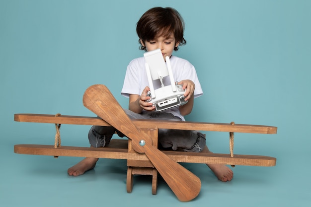 Foto gratuita vista frontal niño niño en camiseta blanca con mando a distancia en azul
