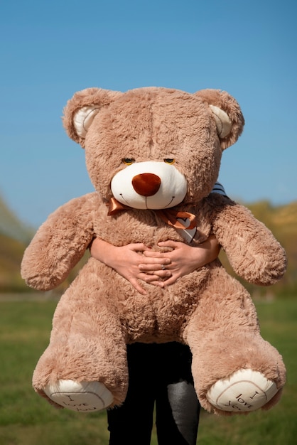 Foto gratuita vista frontal de un niño con un oso de peluche al aire libre