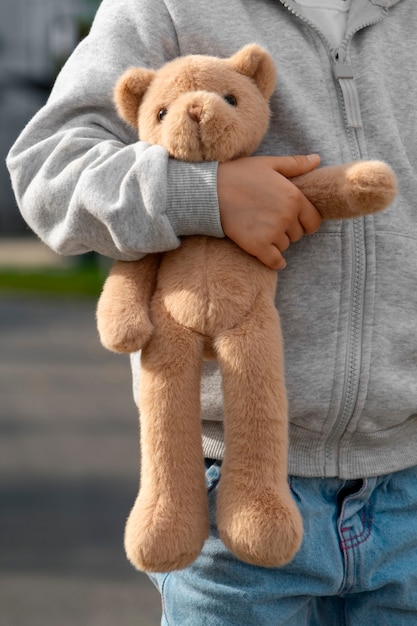 Vista frontal de un niño con un oso de peluche al aire libre