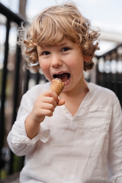 Foto gratuita vista frontal niño pequeño comiendo helado