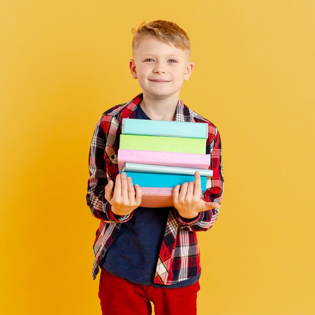 Vista frontal, niño pequeño con pila de libros