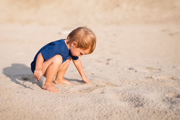 Vista frontal niño pequeño en la playa jugando