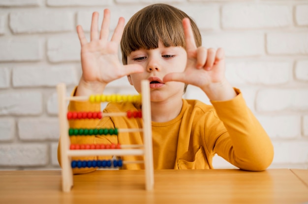 Vista frontal del niño que usa el ábaco para aprender a contar