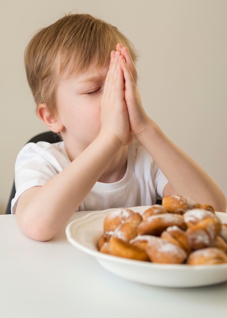 Vista frontal del niño rezando antes de comer