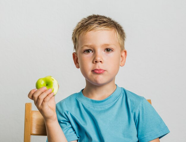 Vista frontal niño en una silla con una manzana