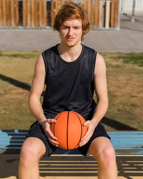 Vista frontal del niño sosteniendo una pelota de baloncesto