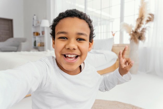 Foto gratuita vista frontal del niño tomando selfie en casa