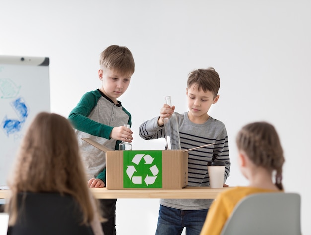 Vista frontal niños aprendiendo a reciclar