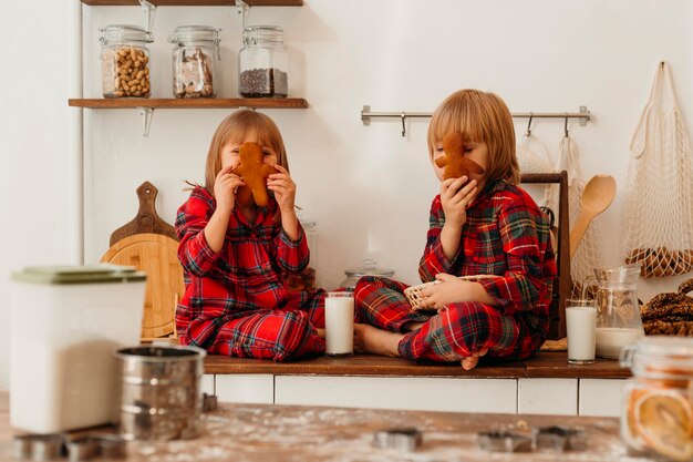 Foto gratuita vista frontal de los niños comiendo galletas juntos el día de navidad