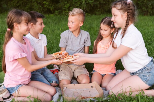 Vista frontal niños compartiendo un poco de pizza