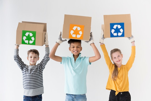 Vista frontal niños felices con cajas de reciclaje