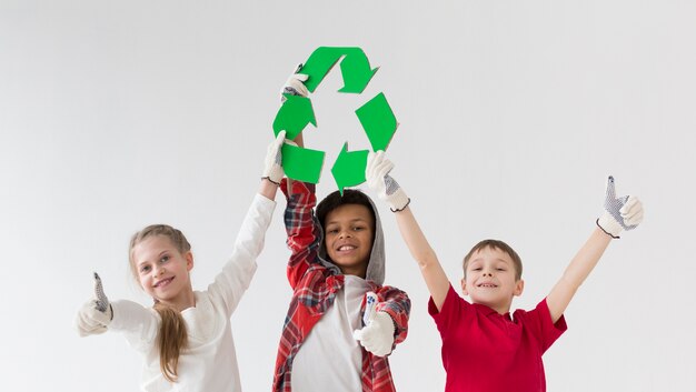 Vista frontal de niños pequeños con cartel de reciclaje