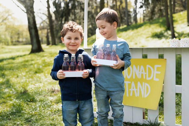 Vista frontal niños pequeños sonrientes con limonada