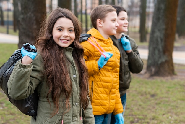 Vista frontal de niños sonrientes llevando bolsas de plástico