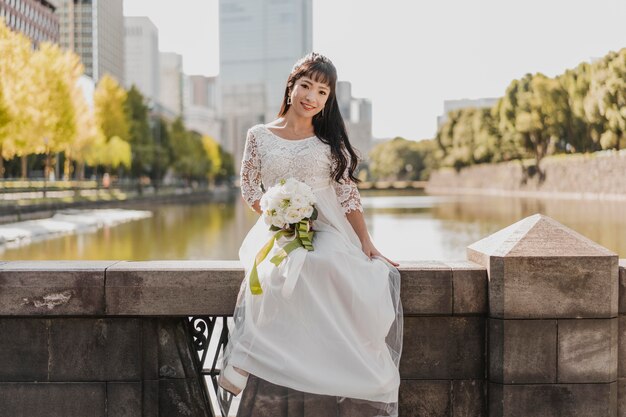 Vista frontal de la novia con ramo de flores posando junto al río