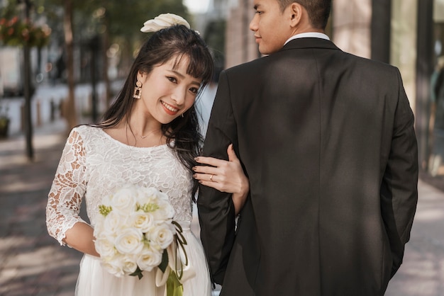 Vista frontal de la novia sosteniendo la mano de su marido al aire libre