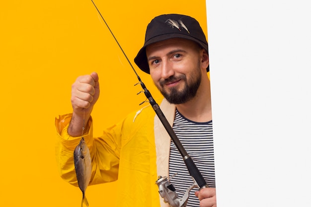 Vista frontal del orgulloso pescador con caña de pescar con captura