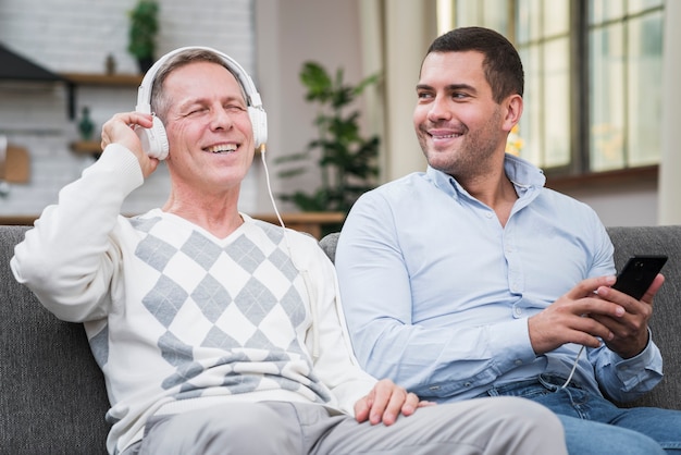 Vista frontal del padre disfrutando de la música del teléfono del hijo