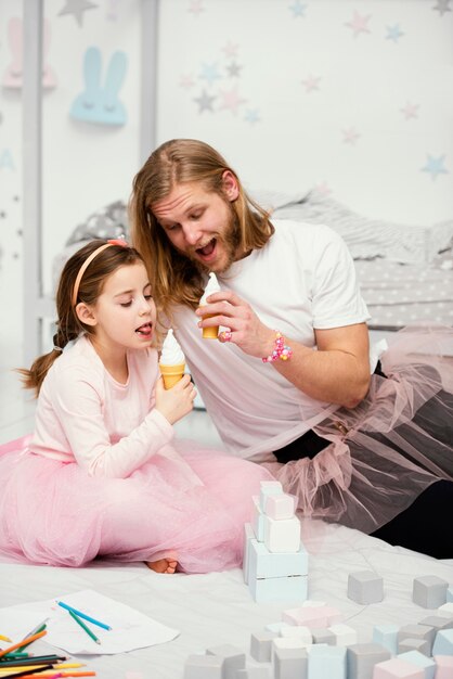 Vista frontal de padre e hija en faldas de tutú comiendo helados