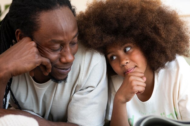 Vista frontal de padre e hija leyendo un libro juntos