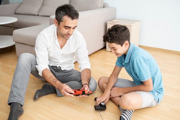 Vista frontal padre e hijo jugando con un carro eléctrico.