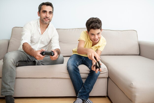 Vista frontal de padre e hijo jugando con los controladores.