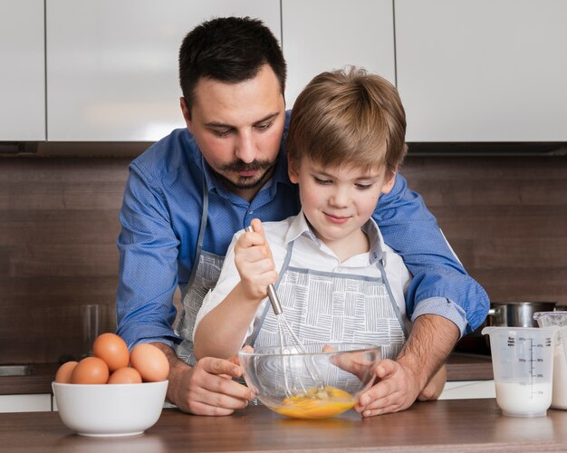 Vista frontal padre e hijo mezclando huevos