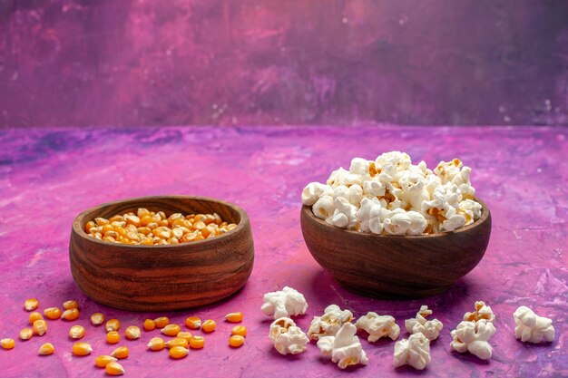 Vista frontal de palomitas de maíz frescas con callos crudos en color rosa claro de cine de película de maíz de mesa