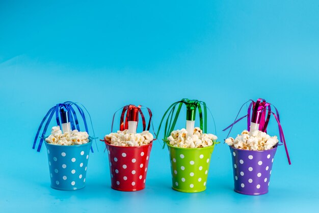 Una vista frontal de palomitas de maíz frescas dentro de cestas multicolores en azul, semillas de bocadillos de películas de cine