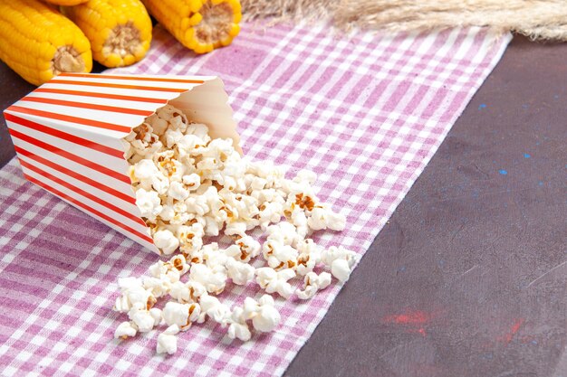 Vista frontal de palomitas de maíz frescas con granos amarillos en la superficie oscura, palomitas de maíz de aperitivo