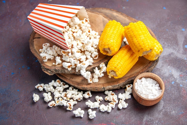 Vista frontal de palomitas de maíz frescas con maíz en rodajas amarillo en el piso oscuro, palomitas de maíz, alimentos