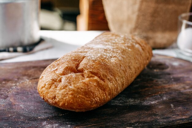 Una vista frontal pan blanco horneado sabroso panadería pastelería entera aislado en el mostrador de madera marrón