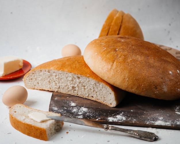 Una vista frontal de pan fresco redondo formado con huevos y flores en la superficie blanca pan pan masa de harina